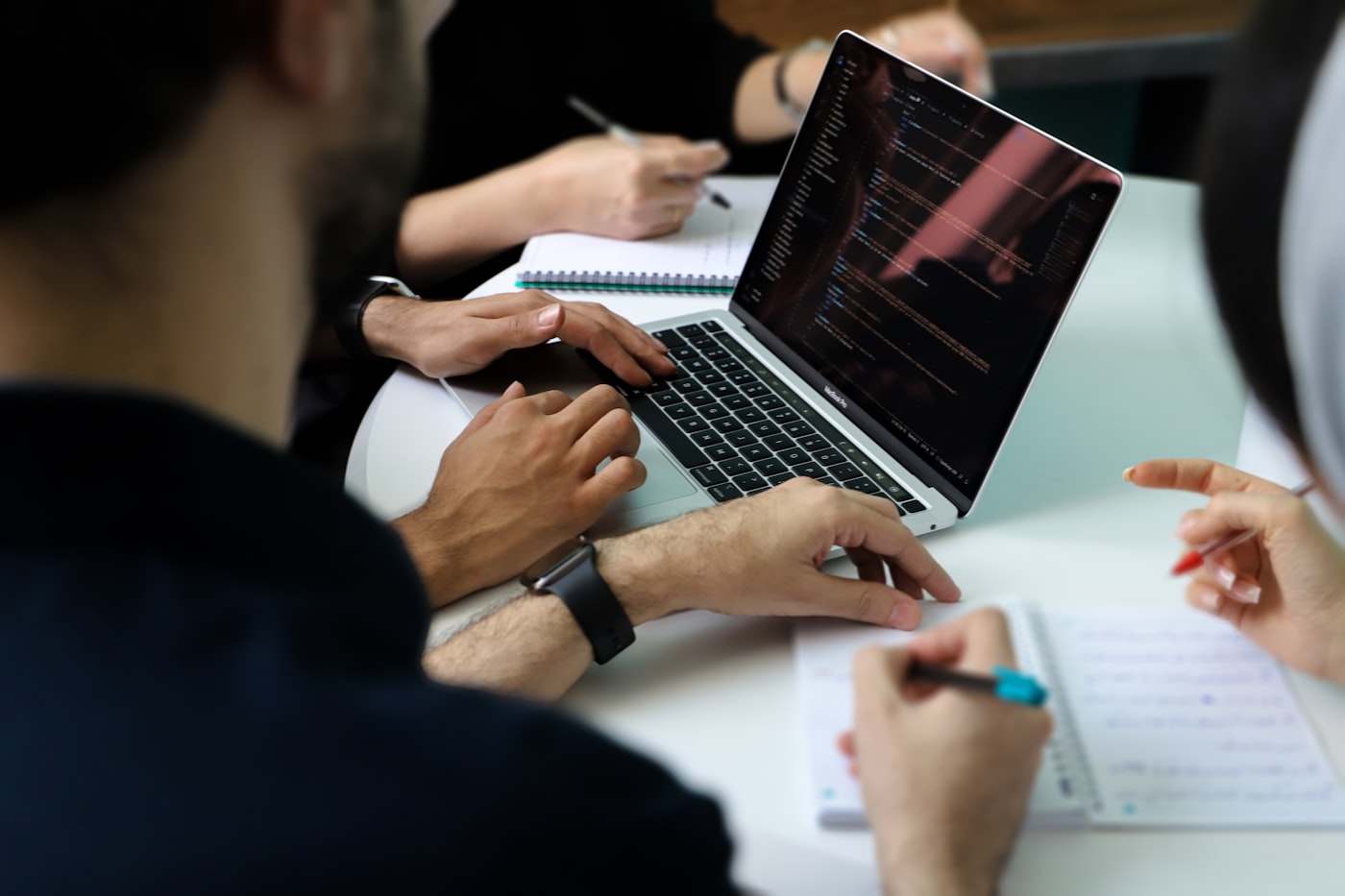 A group of people sitting around a laptop computer. Foto de Fatemeh Rezvani en Unsplash